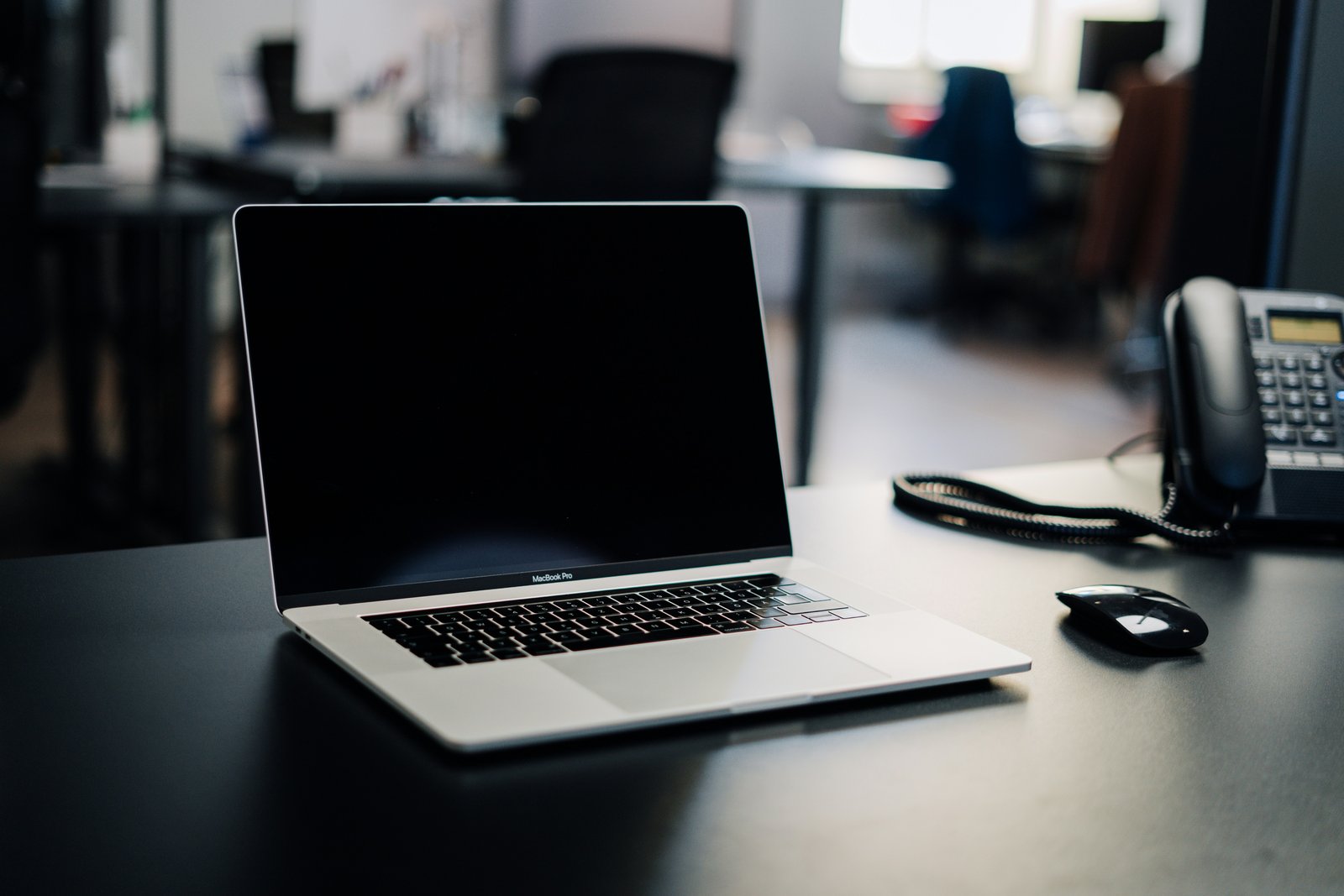 Laptop, muis en bureautelefoon op een bureau in een kantoor