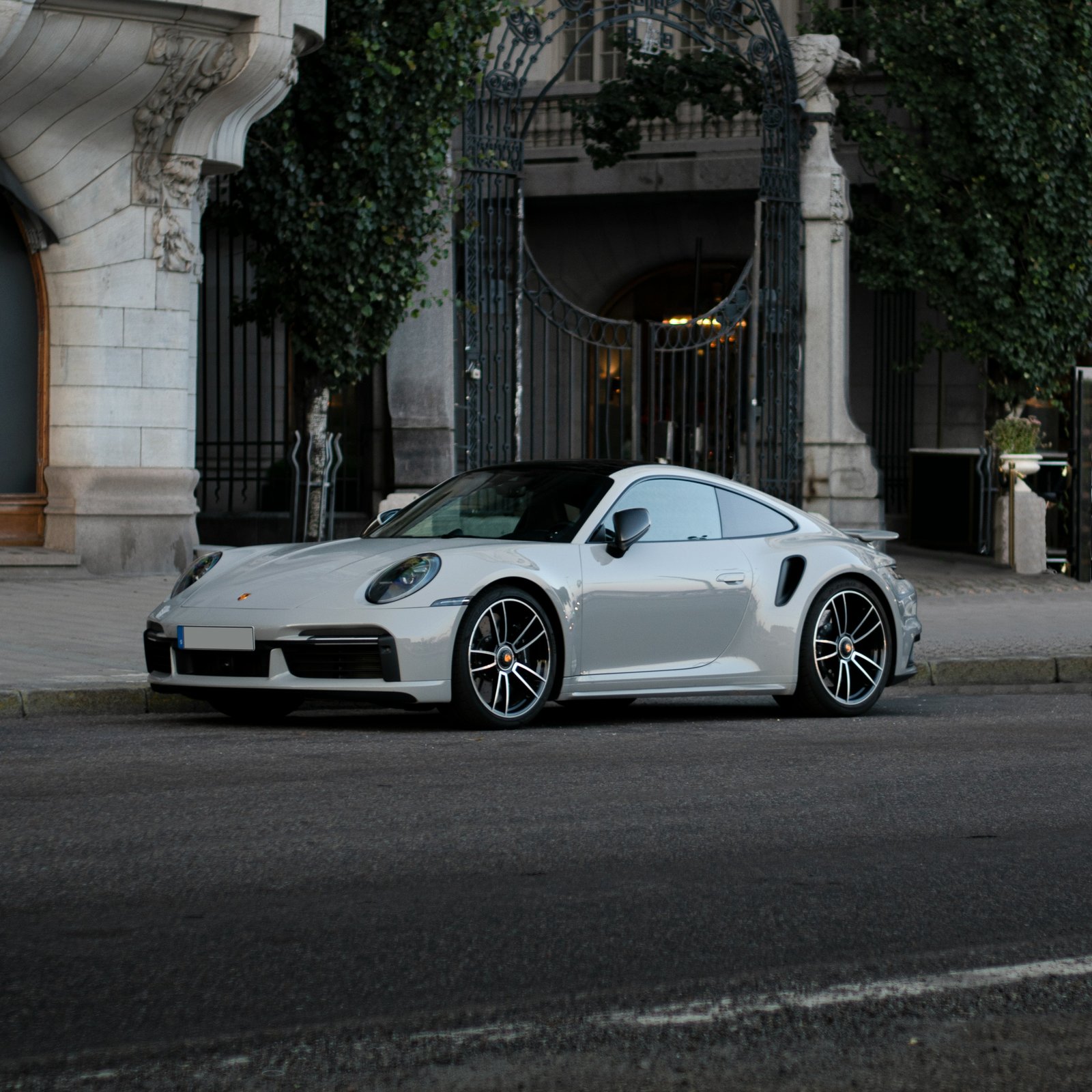 Zilvergrijze Porsche 911 geparkeerd voor een herenhuis